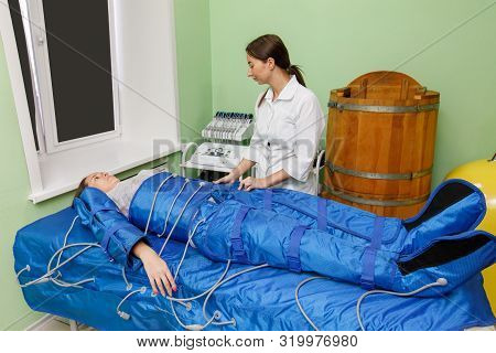Woman In Pressotherapy Suit Lying Down Having Pressure Therapy For Weight Loss In Spa Salon