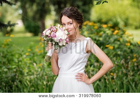 Beautiful Bride In Fashion Wedding Dress On Natural Background. The Stunning Young Bride Is Incredib