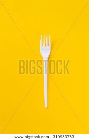 One White Plasti Fork On Saturated Yellow Background As A Symbol Of Consumption. Eco And Fast Food C