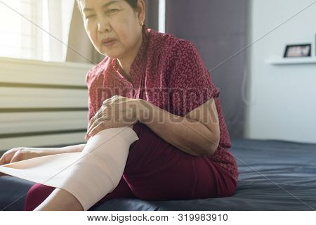 Senior Asian Woman Using Elastic Bandage With Leg,female Putting Bandage On Her Injured Knee