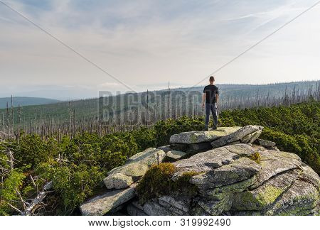 Young Man Tourist Sittiing On Top Of Rock, Sumava National Park And Bavarian Forest, Czech Republic 