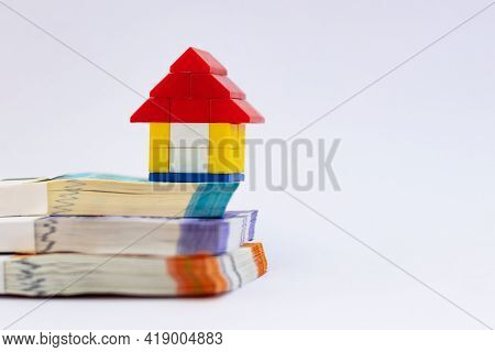 Front Close Up Shot Of Three Bundles Of Notes And A Toy House On Top Showing Real Estate And Investm