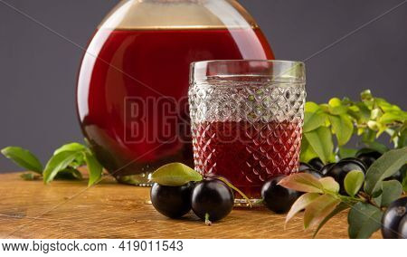 Jaboticaba, Bottle And Glass Of Homemade Brazilian Jaboticaba Liqueur On Wood With Leaves And Branch