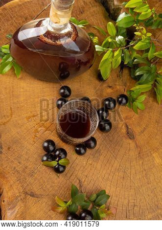 Jaboticaba, Bottle And Glass Of Homemade Brazilian Jaboticaba Liqueur On Wood With Leaves And Branch