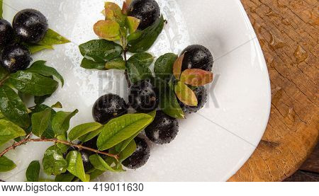 Jabuticaba, Jabuticabas In Detail Inside A White Plate With Branches And Leaves On Rustic Wood, Top