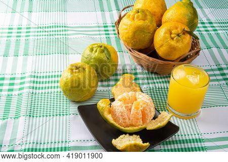 Orange Ponkan, Orange Ponkan Open On A Black Plate, Plus Some Oranges And A Glass Of Juice On A Chec