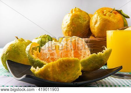 Orange Ponkan, Orange Ponkan Open On A Black Plate, Plus Some Oranges And A Glass Of Juice On A Chec