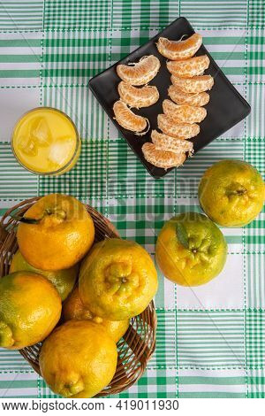 Orange Ponkan, Orange Ponkan Slices On A Black Plate, Plus Some Oranges And A Glass Of Juice On A Ch