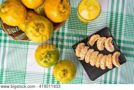 Orange Ponkan, Orange Ponkan Slices On A Black Plate, Plus Some Oranges And A Glass Of Juice On A Ch