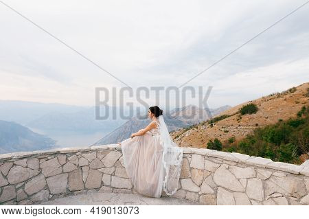 The Bride Sits On The Stone Side Of The Observation Deck On Lovchen Mountain And Looks At The Bay Of