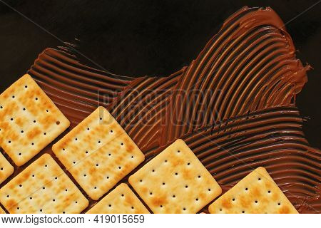 Crackers And Chocolate Paste On Black Background, Cookies Lined Up Like Brickwork, Copy Space For Ba