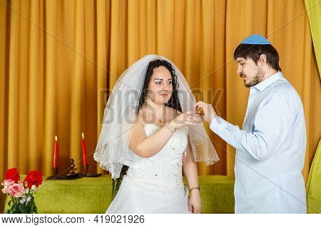 During A Chuppah Ceremony At A Jewish Synagogue Wedding, The Groom Puts A Ring On The Bride's Index 