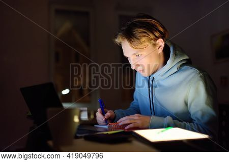 Shocked Teenger Studying Night At Home With Laptop And Tablet Pc. Online Learning, Distance Lessons,