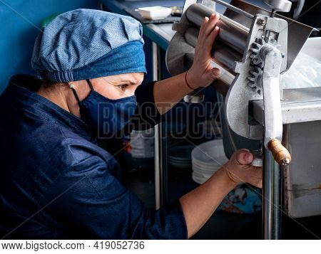 Medellin, Colombia - March 28 2021: Hispanic Woman In Blue Uniform And Cloth Hat Is Putting The Doug