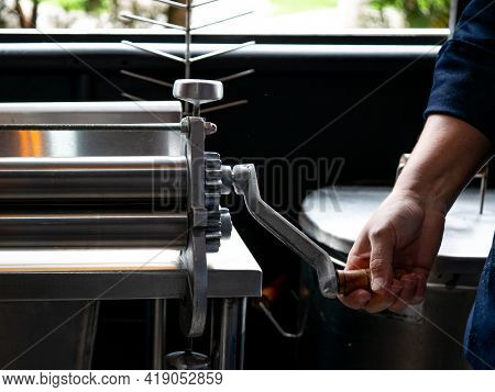 Woman's Hands Holding The Dough Sheeter In The Kitchen