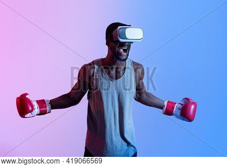 Aggressive Black Sportsman In Vr Headset And Boxing Gloves Shouting During His Workout In Neon Light