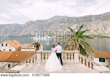 The Bride And Groom Are Standing On The Staircase In The Old City, In Front Of Them Is A Tourist Lin