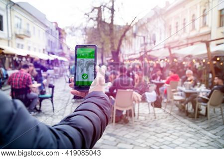 Vaccinated person using immunization certificate on smartphone at the restaurant or terrace. 
