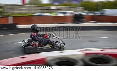 A Panning Shot Of A Racing Kart As It Circuits A Track.