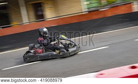 A Panning Shot Of A Racing Kart As It Circuits A Track.