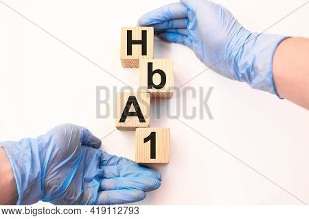 A Doctor Wearing Gloves Holds Wooden Cubes With The Inscription Hba1, Medical Concept