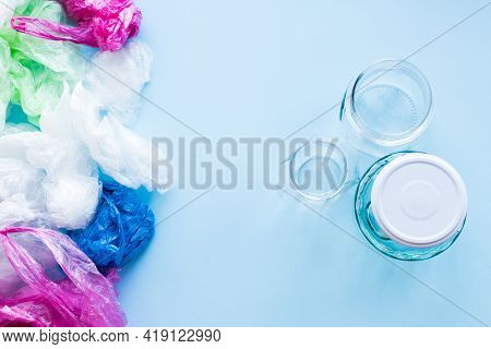 Many Disposable Plastic Bags Vs Reusable Glass Jars On A Blue Background. Zero Waste Shopping. Susta