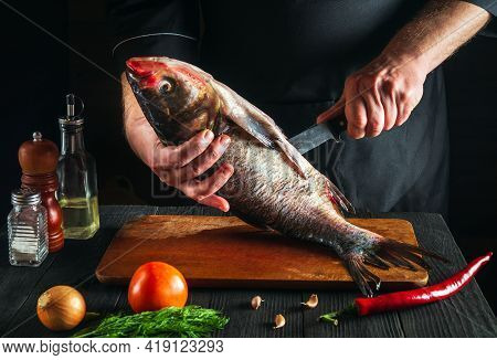 Chef Is Cleaning A Bighead Carp Fish. Working Environment In The Restaurant Kitchen. Fish Diet Conce