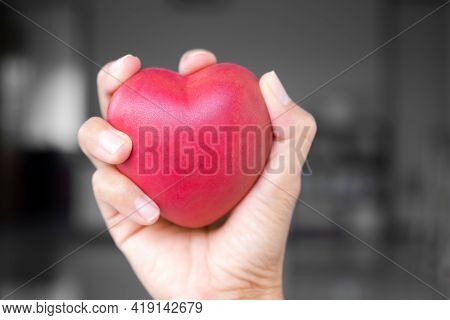 Broken Heart Concept. Close Up Hand Woman Holding And Constrain Red Heart Shape On Blur Black And Wh
