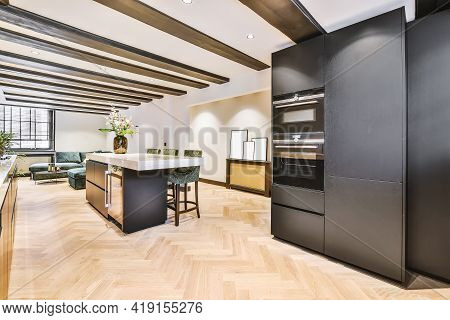 Interior Of Contemporary Open Plan Kitchen With Built In Appliances And Dark Cabinets Under Ceiling 