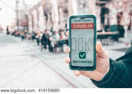 Vaccinated person using immunization certificate on smartphone at the restaurant or terrace. 