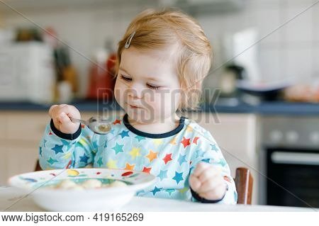 Adorable Baby Girl Eating From Spoon Vegetable Noodle Soup. Food, Child, Feeding And Development Con