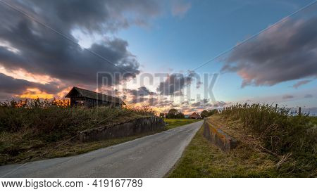 Road Passage Through Dike At Sunset Under Beautiful Clouded Sky. Usquert, Groningen, Netherlands