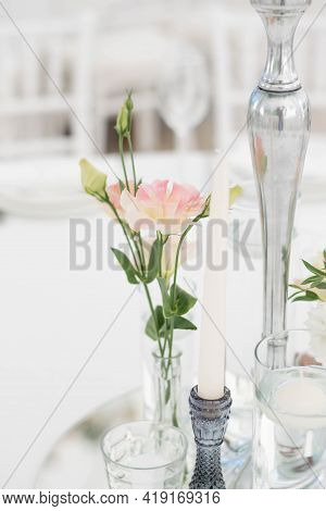 Close-up Of A Wedding Dinner Table At Reception. Fresh Flowers And Candles On Mirros Plate. Wedding