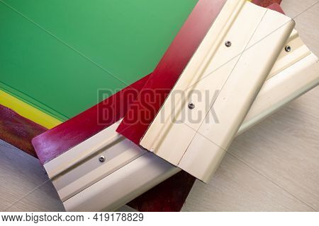 Serigraphy Silk Screen Print Process At Clothes Factory. Frame Stencil And Squeegee.