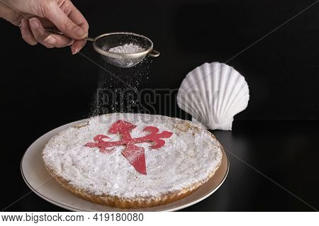 Woman Pouring Sugar For Decorated Tarta De  Santiago Or St. James Cake, Famous Spanish Almond Cake