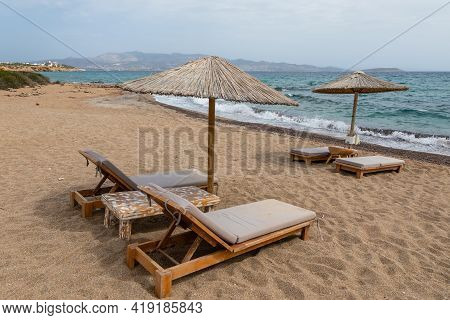 View Of Sandy Soros Beach On The Greek Island Of Antiparos With Sunbeds And Umbrellas. Cloudy Day.
