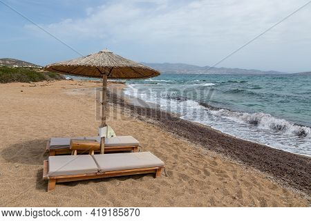 View Of Sandy Soros Beach On The Greek Island Of Antiparos With Sunbeds And Umbrellas. Cloudy Day.