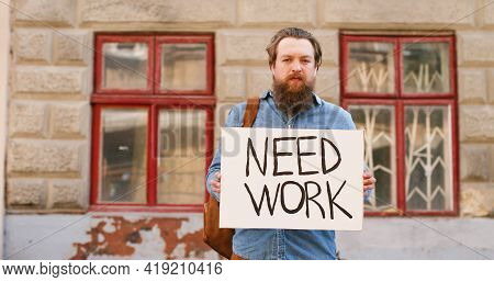 Portrait Shot Of Unemployed Caucasian Young Man Standing On Street In Town And Showing Poster With N