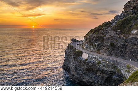 Winding Road Along Rocky Coast Of Cap Corse Peninsula On Corsica Island At Sunset, France