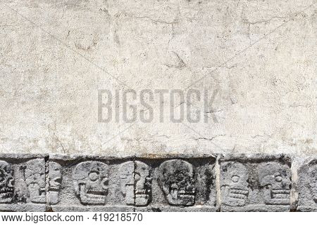 Horizontal banner with stone wall texture and bas-relief carving with human skulls, pre-Columbian Mayan civilization. Day of the Dead (El Dia de Muertos) holiday background. Copy space for text