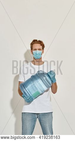 Picture Of A Young Deliveryman Standing Isolated Over The White Wall And Watching In Camera, Has A R