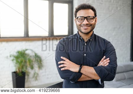 Headshot Of Skilled Hindu Male Employee Standing With Arms Crossed In Modern Office, Successful Conf