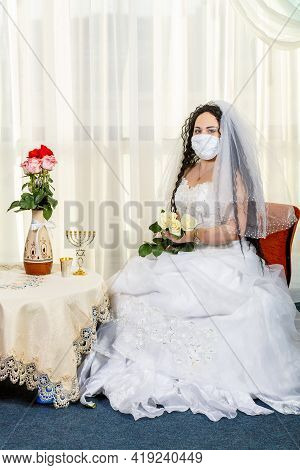 A Jewish Bride Sits In A Synagogue Before A Chuppa Ceremony During A Pandemic Wearing A Medical Mask