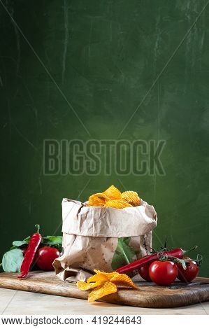 Potato Chips In A Paper Bag. Potato Chips With Chili And Tomatoes. Vertical Frame.