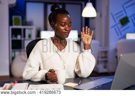 Black Businesswoman Saying Hello During Video Call Sitting At Desk