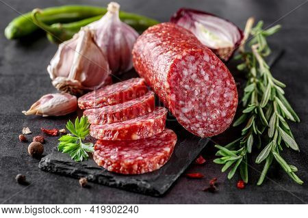 Traditional Smoked Salami Sausage With Spices.salami Sausage Slices On A Black Chopping Board. Dark 