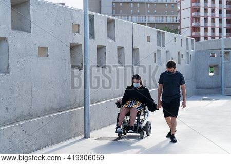 Young Disabled Woman In Wheelchair And Her Loving Boyfriend Or Husband Holding Hands During Covid 19