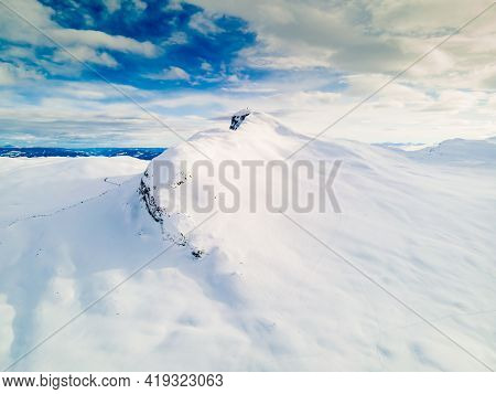 Panoramic View Of A Snow Capped Mountain Peak With Clouds And Blue Skies.