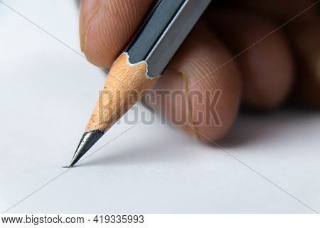 Close Up Shot Of Fingers Holding A Pencil And Ready To Write On The White Paper -start Concept