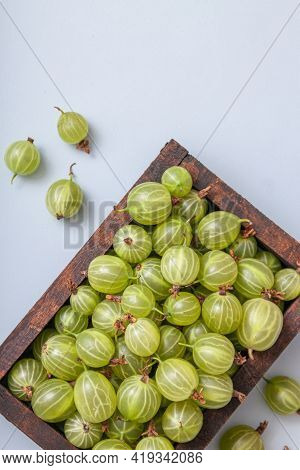 Ripe Green Gooseberry Berry In Wooden Box. Green Gooseberry On Light Blue Background. Top View